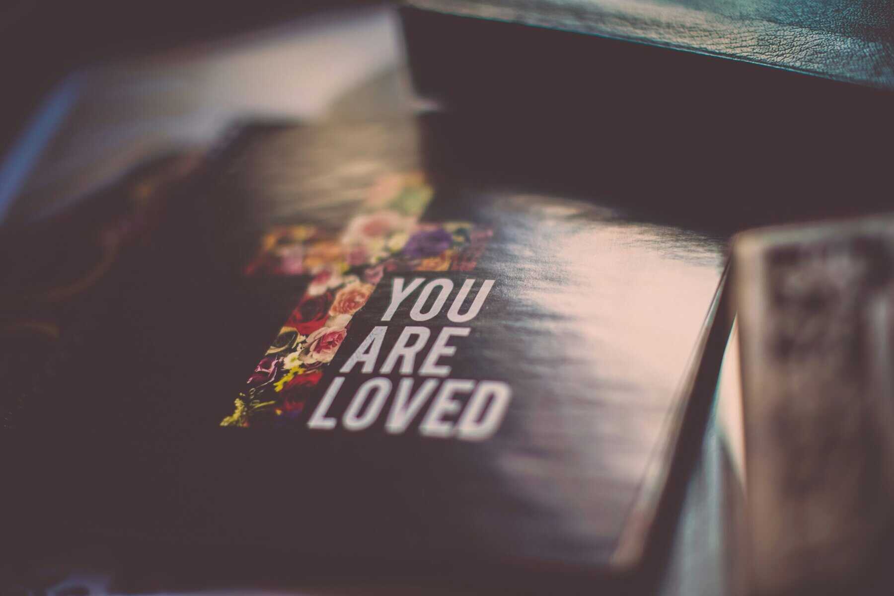 Bible with "you are loved" written atop.