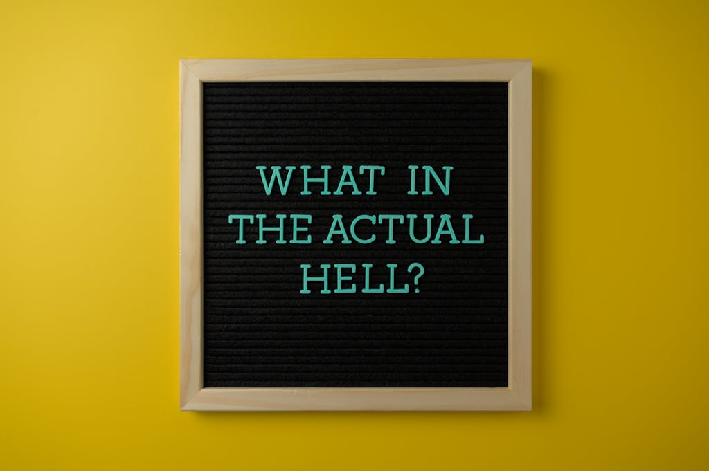 Letter board with humorous quote 'What in the actual hell?' on a vibrant yellow backdrop.